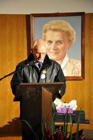Slavnostni govornik s sliko ustanoviteljice in dolgoletne učiteljice Mije Markež v ozadju