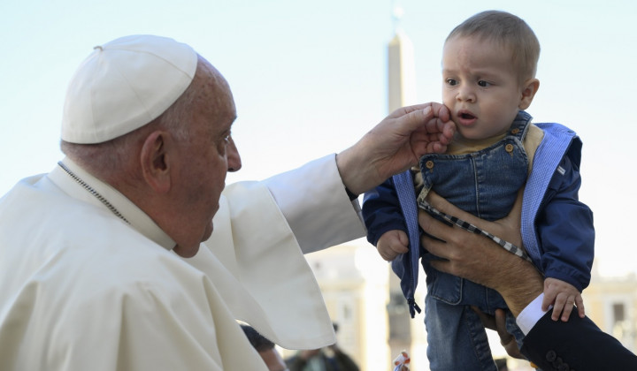 Papež pred avdienco pozdravlja otroka (foto: Vatican media)